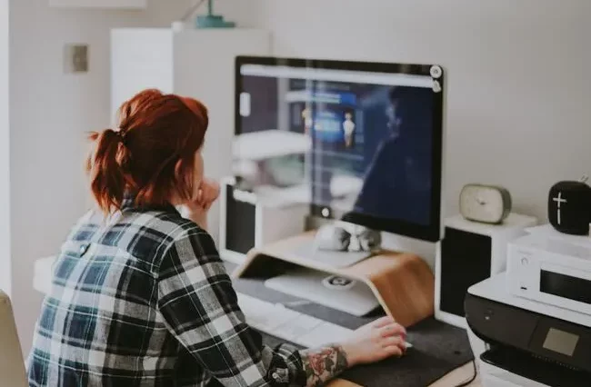 Eine rothaarige Frau sitz vor dem Computer und lernt Fachinformatik