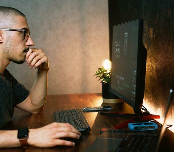 Ein Mann sitzt an einem Schreibtisch vor einem Computer.
