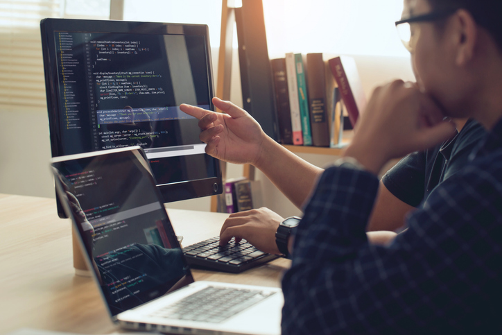 Web Developer schreibt Code am Desktop PC