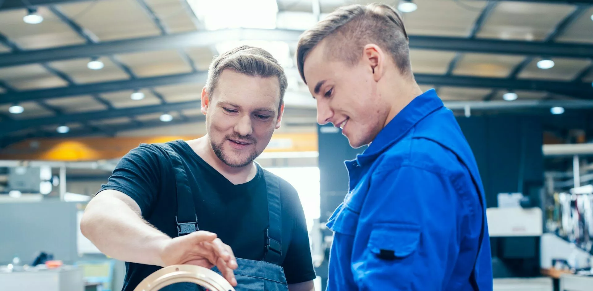 Meister zeigt seinem Auszubildenden ein Werkstück