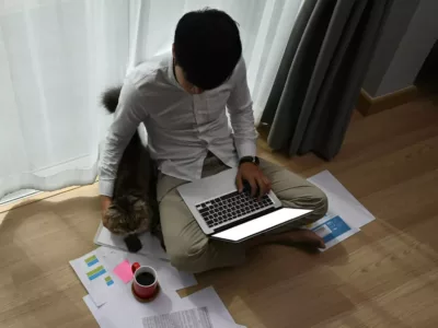 Student sitzt auf einem Holzboden mit Laptop