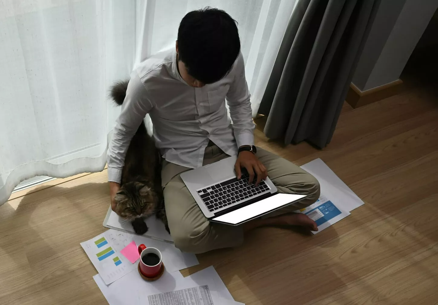 Student sitzt auf einem Holzboden mit Laptop