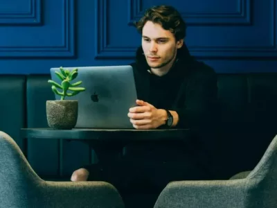 Student sitzt in einem blauen Zimmer vor seinem Laptop